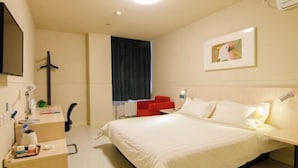 Une chambre d’hôtel avec un lit, une table de chevet, une lampe et une chaise rouge.