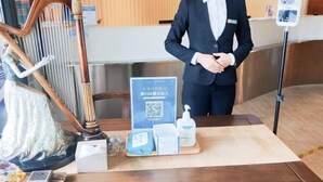 A hotel reception area with a wooden desk, a statue, a QR code sign, and a self-service kiosk. - Jinjiang Inn (Baotou Railway Station) (Baotou)