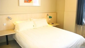 Une chambre d’hôtel avec un lit, une table de chevet, une lampe, un téléphone et un tableau au mur.