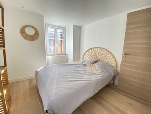 Ein Schlafzimmer mit Bett, Fenster, Holztür und einer runden Wanddekoration.