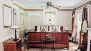 A room with a wooden bench, a small table with a vase, a ceiling fan, and a large mirror. - Charming Victorian home (Groton)