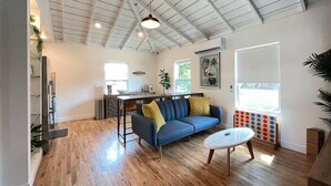 A spacious living area with a blue sofa, wooden flooring, and a ceiling with exposed beams. - Stylish Apt Near Disney and Airport (Santa Ana)