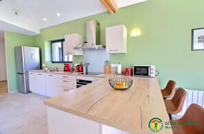 A modern kitchen with white cabinets, a wooden island, and a microwave. - E-Tal Ar Wazh - CRACH (CRACH)