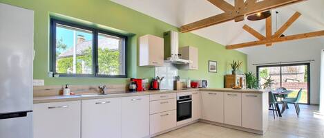 A modern kitchen with white cabinets, a built-in oven, and a large window.