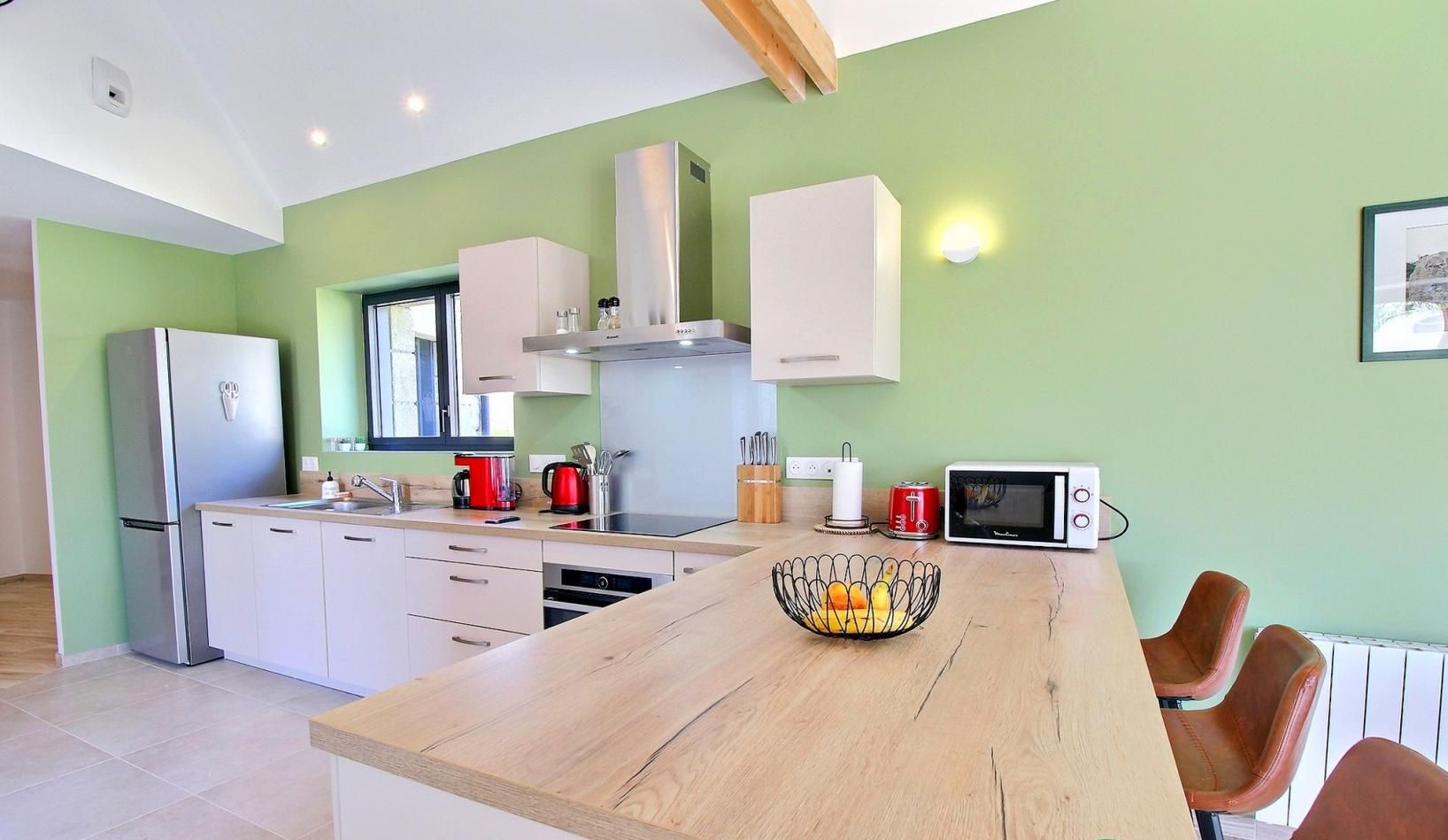 Een moderne keuken met witte kasten, een houten keukeneiland en een magnetron.