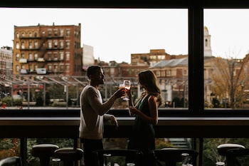 A balcony with a city view, featuring a table and chairs, and a glass railing. at Canopy By Hilton Boston Downtown