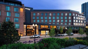 A modern hotel with multiple floors, large windows, and a well-lit entrance. - Canopy By Hilton Boston Downtown (Boston)