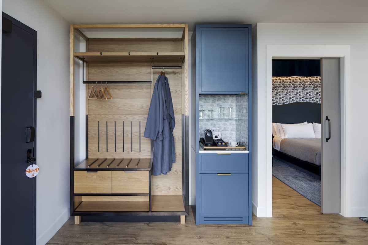 A compact bedroom with a bed, a bedside table with a lamp, and a wardrobe with hanging space.
