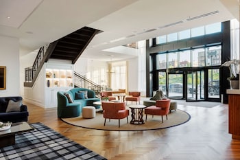 A modern living room with a tufted sofa, a black console table, two armchairs, and a chandelier. at Canopy By Hilton Boston Downtown