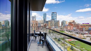 A balcony with a city view, featuring a table and chairs, and a glass railing. - Canopy By Hilton Boston Downtown (Boston)