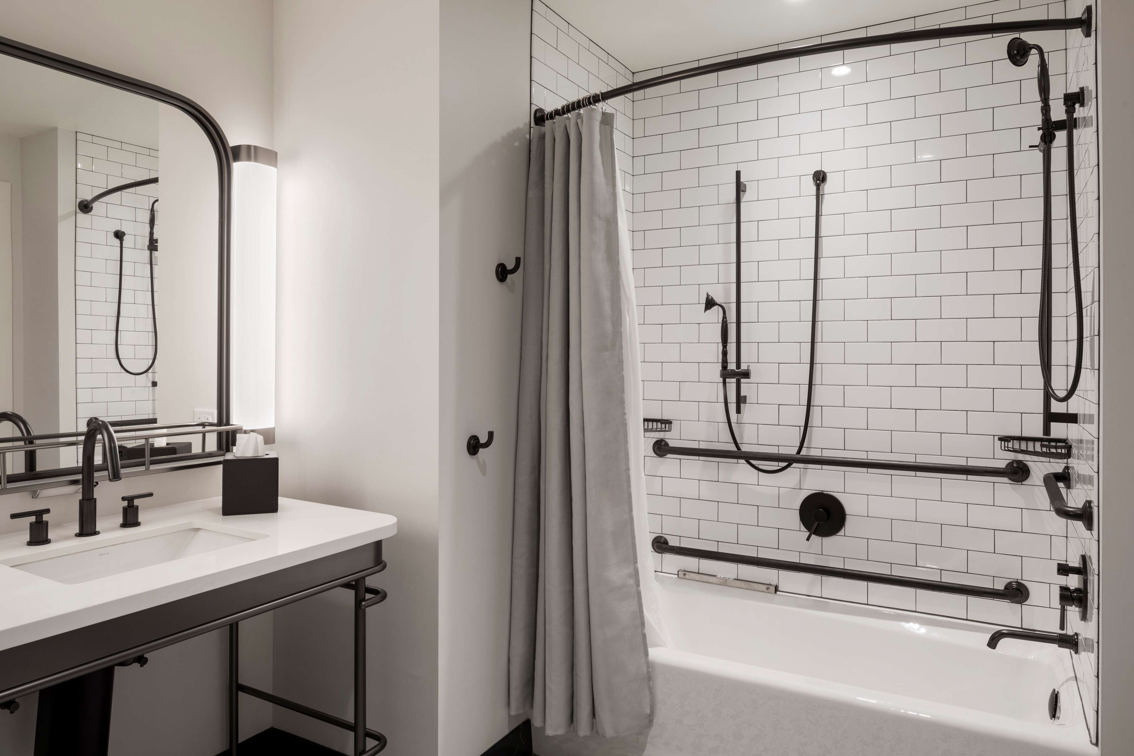A modern bathroom with a white-tiled shower, a bathtub, and a sink with a mirror.