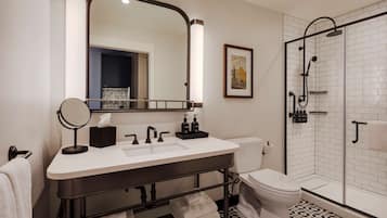 Un baño moderno con un espejo grande, un lavamanos, un inodoro y una zona de ducha.