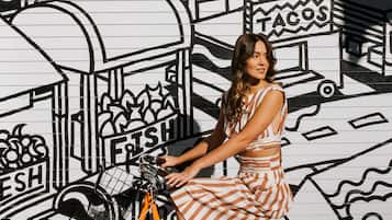 A person sitting on a bicycle in front of a wall with a mural.