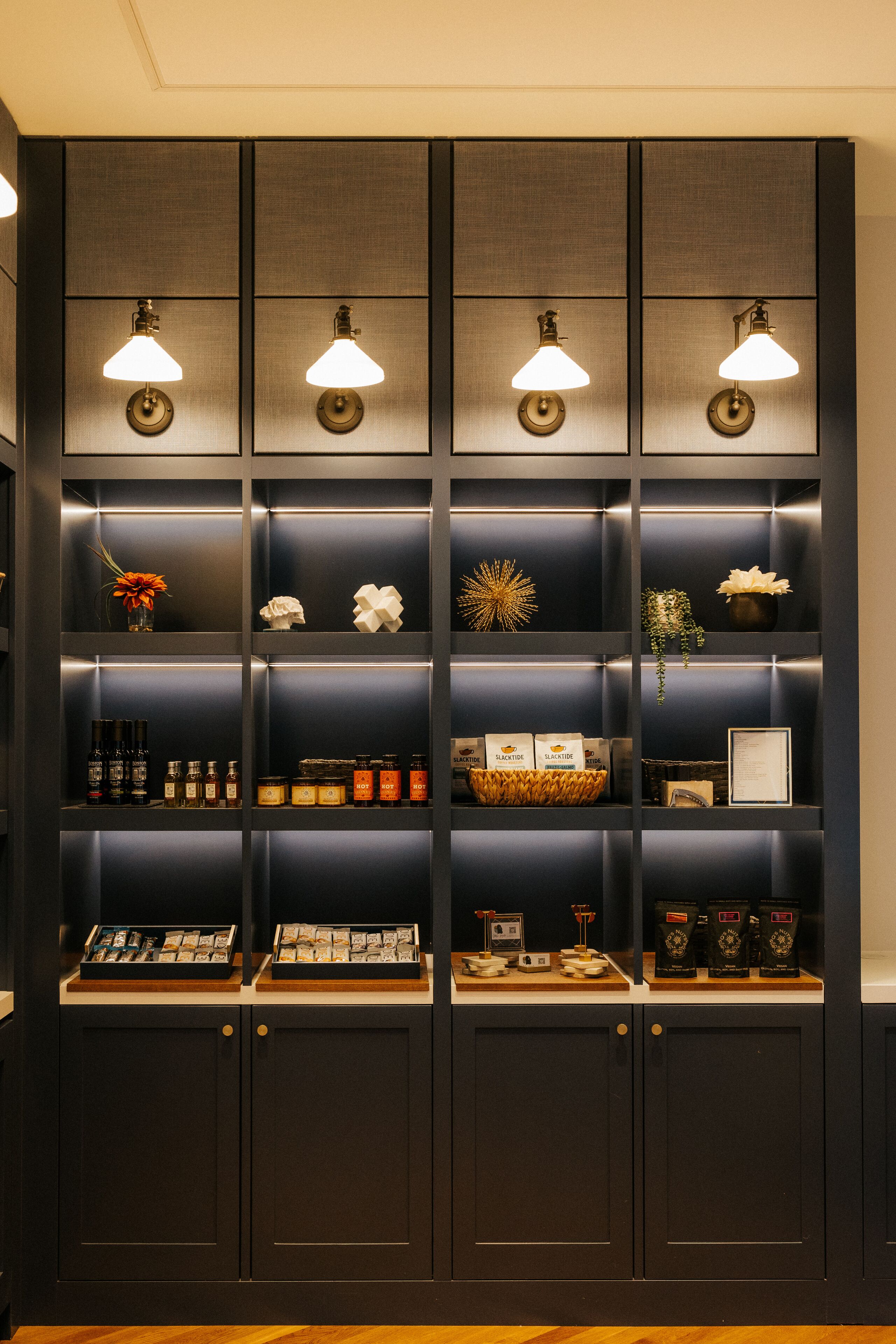 A dark wood-paneled display cabinet with multiple shelves, each illuminated by a single lamp.