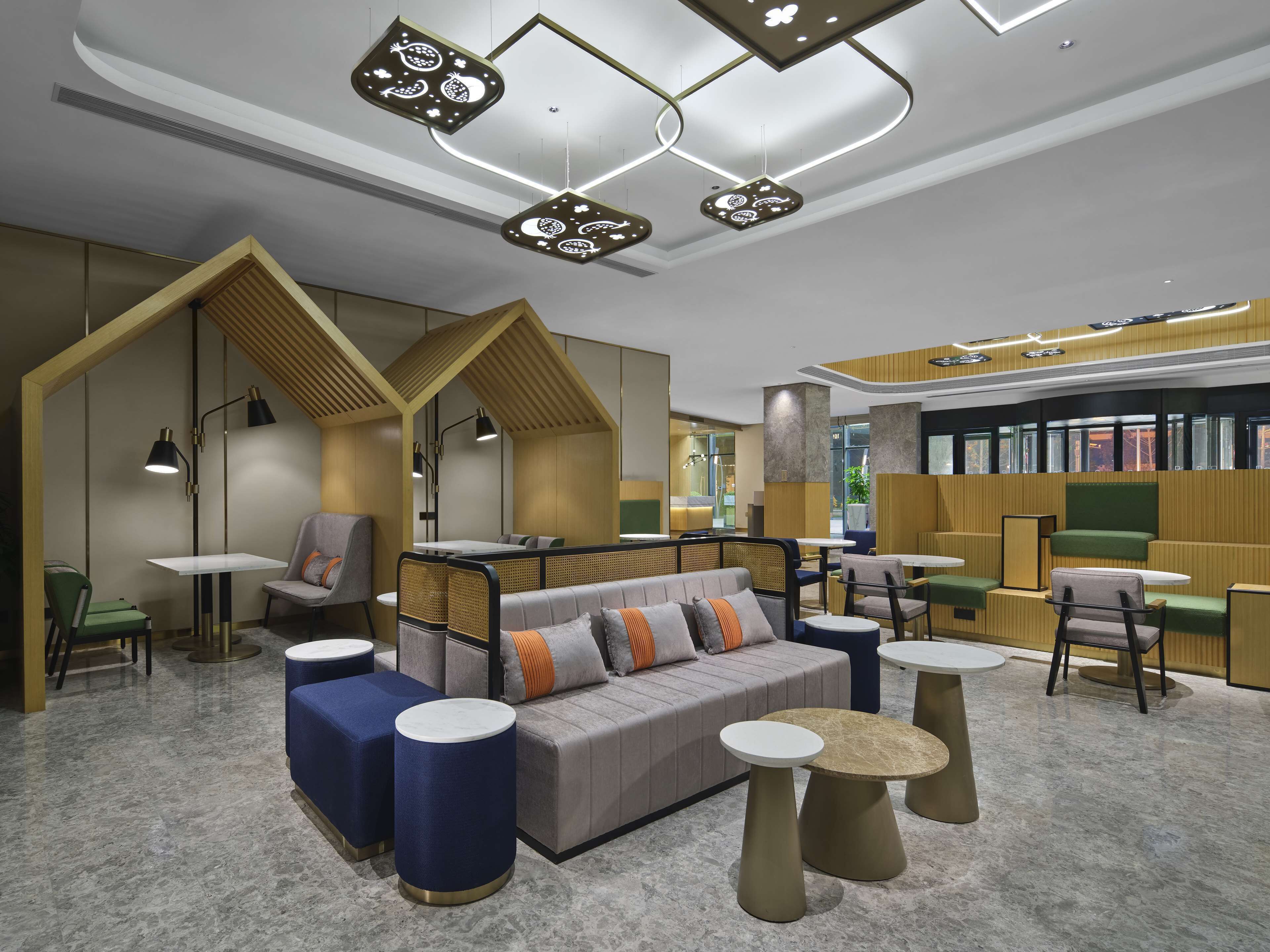 A modern lounge area with seating, tables, and a bookshelf.