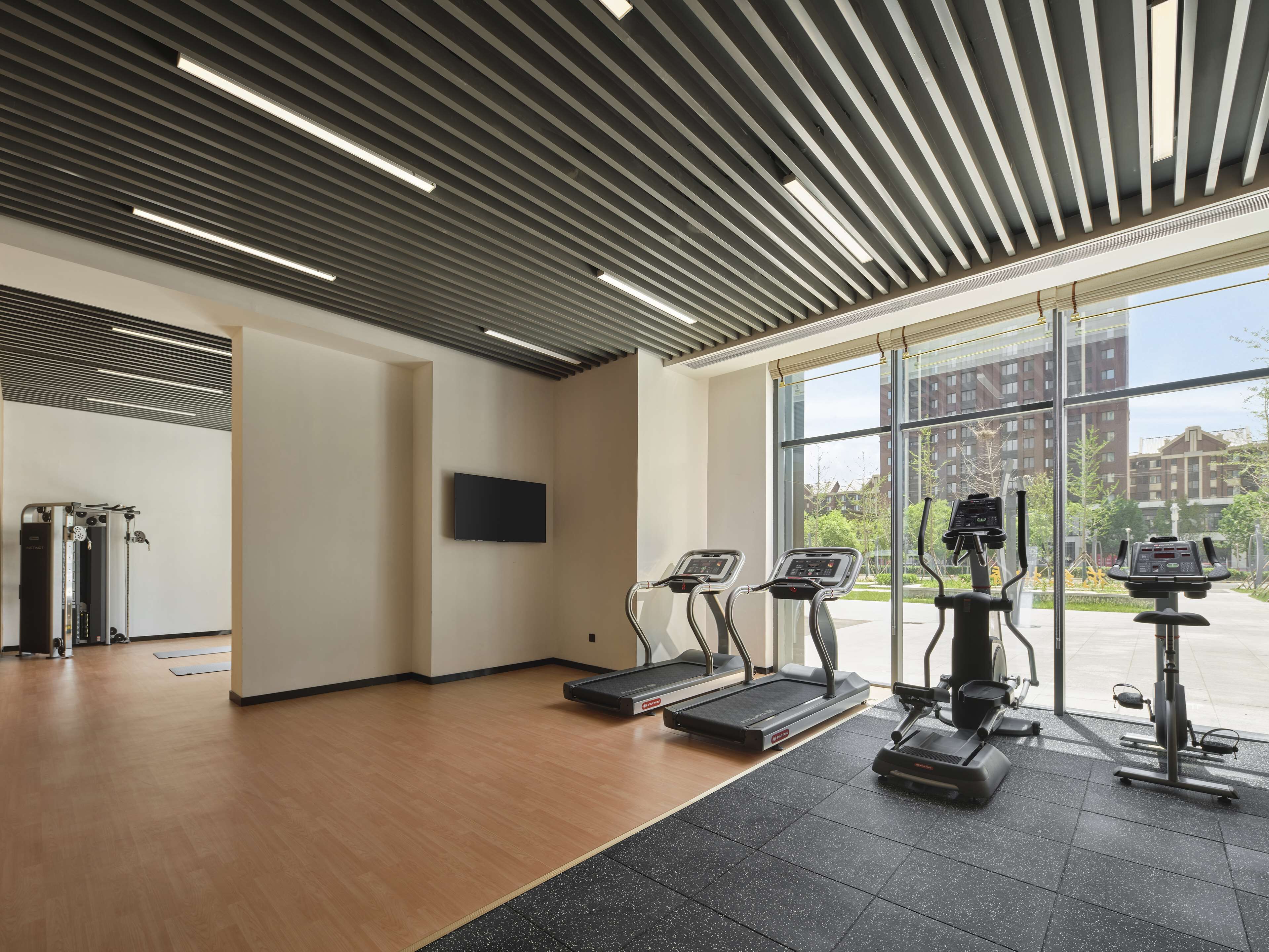 Un gimnasio moderno con cintas de correr, elípticas y máquinas de pesas.