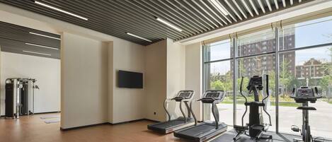 Un gimnasio moderno con cintas de correr, elípticas y máquinas de pesas.