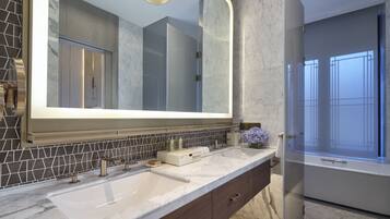 Une salle de bain moderne dotée d’un grand miroir, de deux lavabos, d’un meuble-lavabo avec un plan de travail en marbre et d’un espace douche avec une porte en verre.