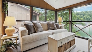 Ein modernes Wohnzimmer mit großem Fenster, einer Couch, einem Beistelltisch und einer Lampe.
