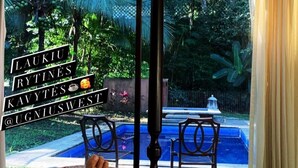 A bed with a patterned blanket, a view of a garden, and a balcony with chairs. - Casa Safari Maganda located in the middle of
paradise. (Tarcoles)