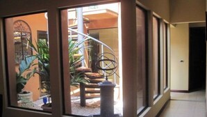 A hallway with a window view of a patio area, including a metal sculpture and potted plants. - Casa Safari Maganda located in the middle of
paradise. (Tarcoles)