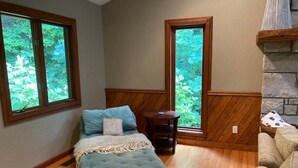 A bedroom with a bed, a small table, and a view of greenery through large windows. - Private Family Mountain Getaway 6mi to Asheville (Fairview)