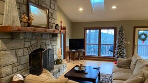 A cozy living room with a stone fireplace, a television, and a Christmas tree. - Private Family Mountain Getaway 6mi to Asheville (Fairview)