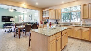 A spacious kitchen with granite countertops, wooden cabinets, and a dining area with a table and chairs. - Golfer's Paradise: Oro Valley Home w/ Pool! (Oro Valley)