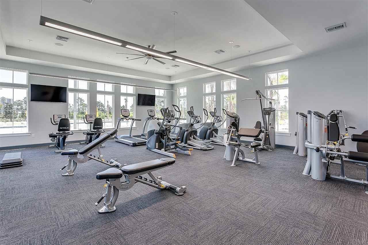 Ett modernt gym med olika träningsmaskiner, stora fönster och en ren och rymlig inredning.