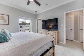 A bedroom with a bed, a TV, a dresser, and a door.