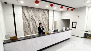 En moderne receptionsdisk med en marmorvæg, en sort bordplade og røde lanterner i loftet.