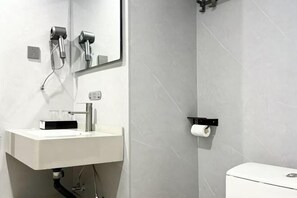 A modern bathroom with a white sink, a mirror, a hairdryer, and a toilet. - Dehua Longhu Boyue Hotel (Dehua)