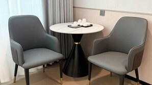 Et rum med to grå stole omkring et lille rundt bord med sort fod.