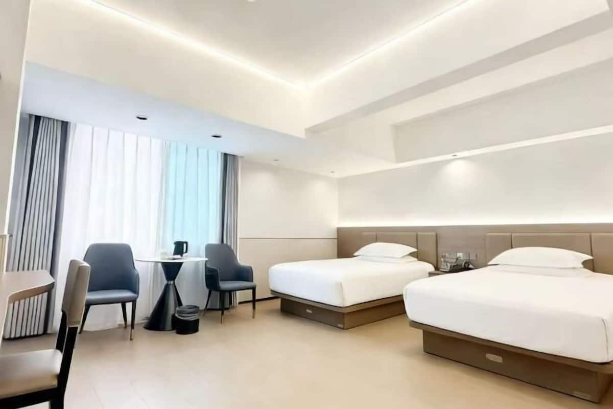 Ein Hotelzimmer mit zwei Betten, einem Schreibtisch, Stühlen und einem fenster mit Vorhängen.