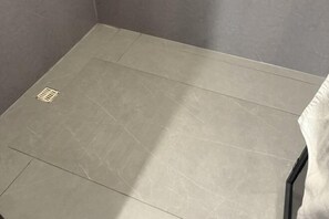 A bathroom with a tiled floor and a drain.