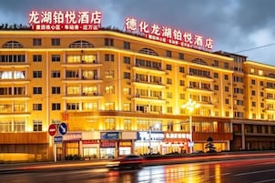 A multi-story hotel with a prominent sign, multiple windows, and a well-lit facade.