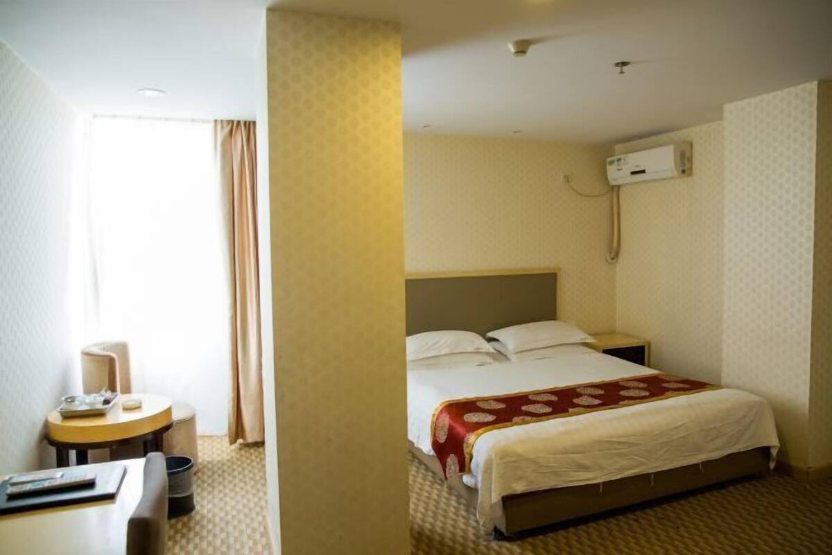 Ein Hotelzimmer mit einem Bett, einem Nachttisch, einem Sessel und einem Schreibtisch.