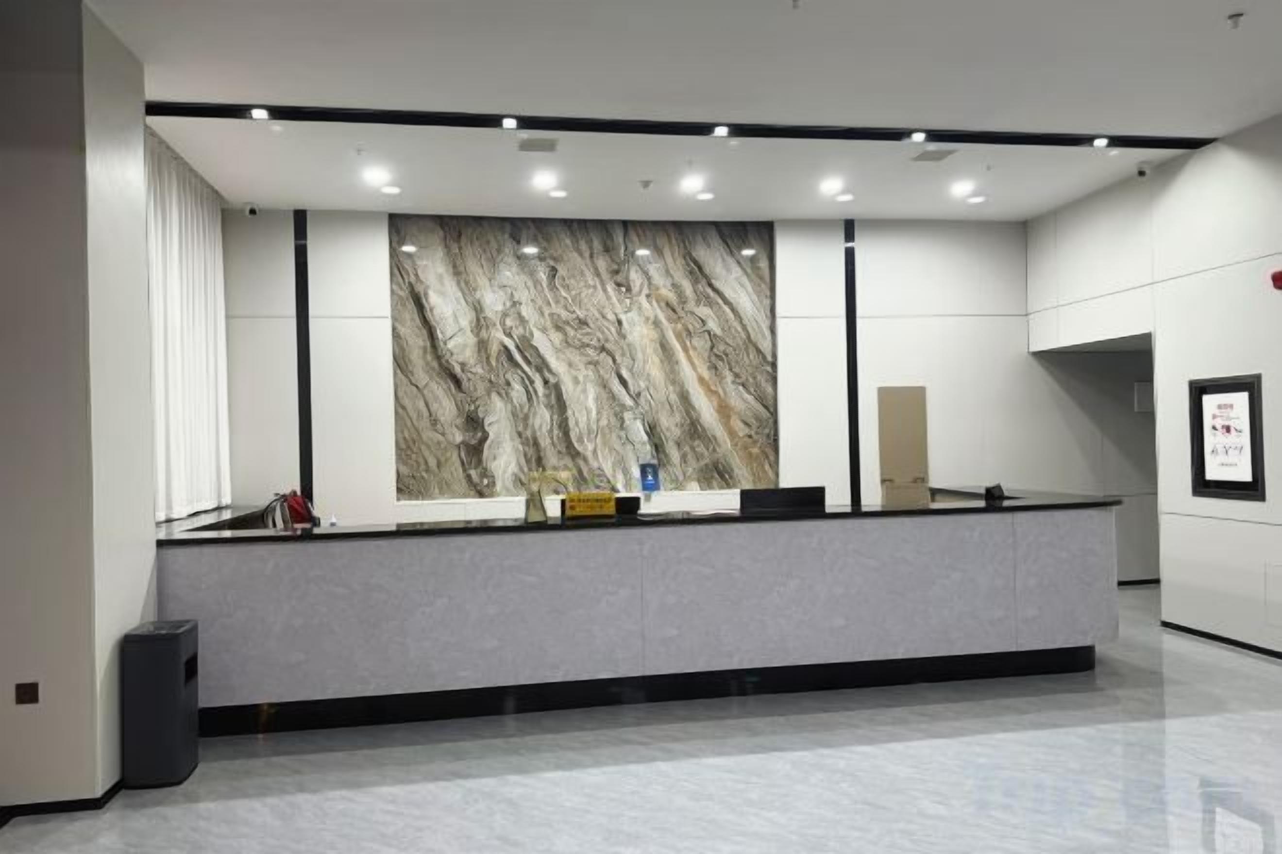 A reception area with a marble wall, a reception desk, and a trash bin.