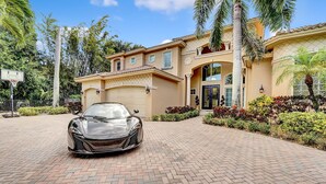 Une maison de luxe avec une allée, une voiture de sport et un panier de basketball.
