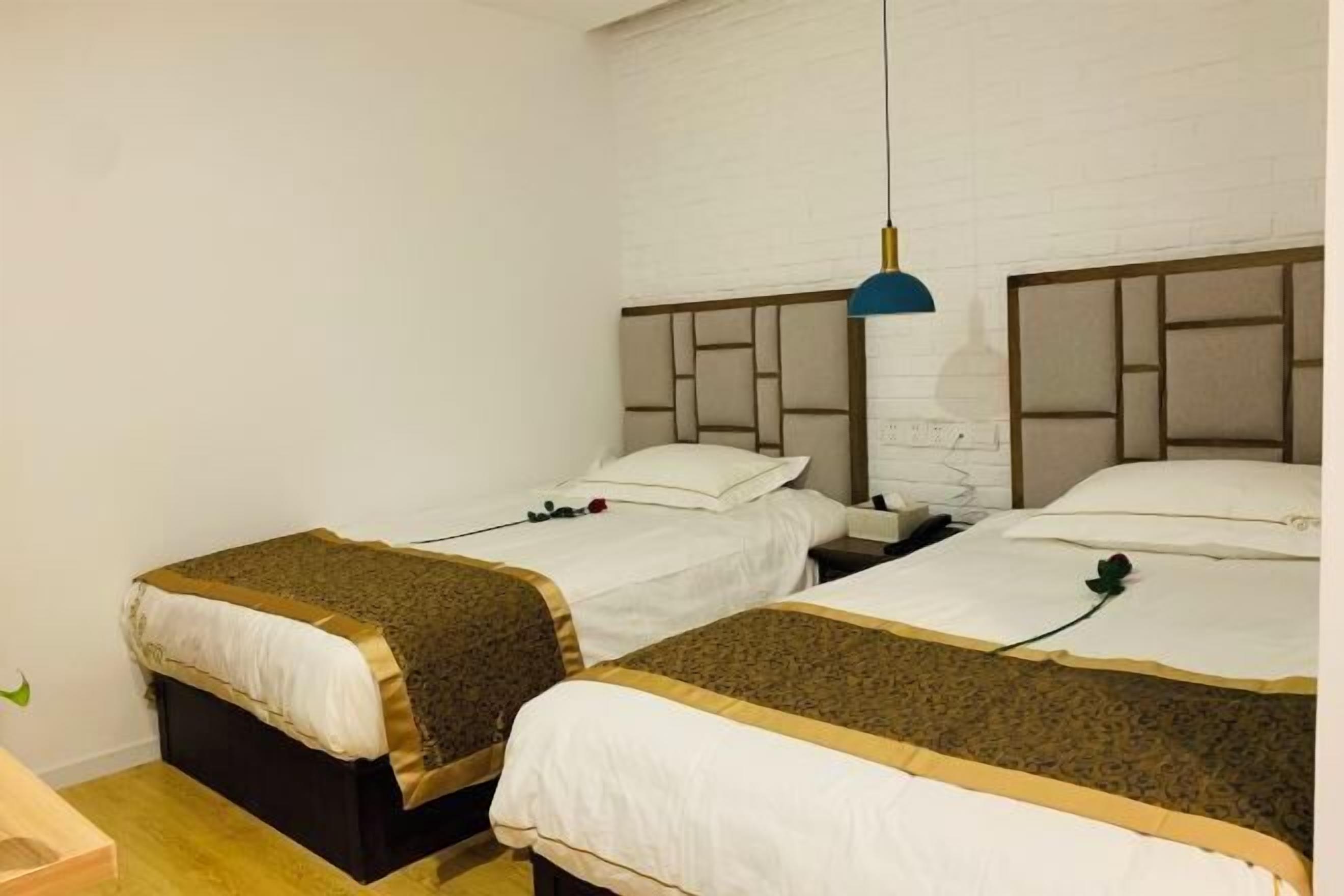 Ein Hotelzimmer mit zwei Betten, einer weißen Ziegelwand und einer blauen Pendelleuchte.