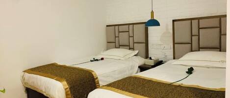 Ein Hotelzimmer mit zwei Betten, einer weißen Ziegelwand und einer blauen Pendelleuchte.
