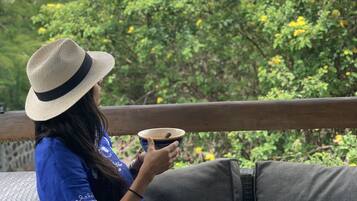 Une personne est assise sur un canapé gris, devant une table blanche, et tient une tasse à la main.