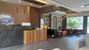 A modern reception area with a wooden reception desk, a digital screen, and a seating area with chairs and a sofa. - Nanchang 520 Youth Hotel (Mailu Campus Center store of University of Finance and Economics) (Nanchang)
