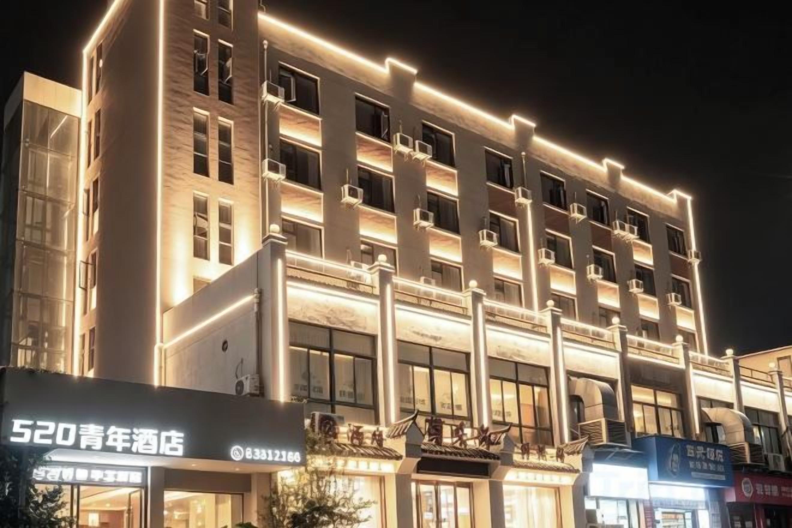 Un hotel de varios pisos con fachada moderna, señalización iluminada y entrada visible.