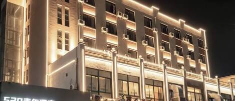 Un hotel de varios pisos con fachada moderna, señalización iluminada y entrada visible.