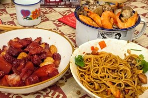 Una mesa con tres platos: un plato de carne salteada, un tazón de fideos y un tazón de mariscos.