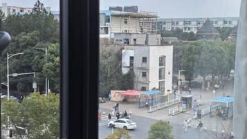 A view of a street with buildings, trees, and a few people.