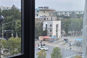 A view of a street with buildings, trees, and a few people. - Nanchang 520 Youth Hotel (Mailu Campus Center store of University of Finance and Economics) (Nanchang)