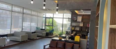 A modern interior with seating areas, a reception desk, and large windows.