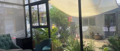 A conservatory with a glass enclosure, seating area, and potted plants.